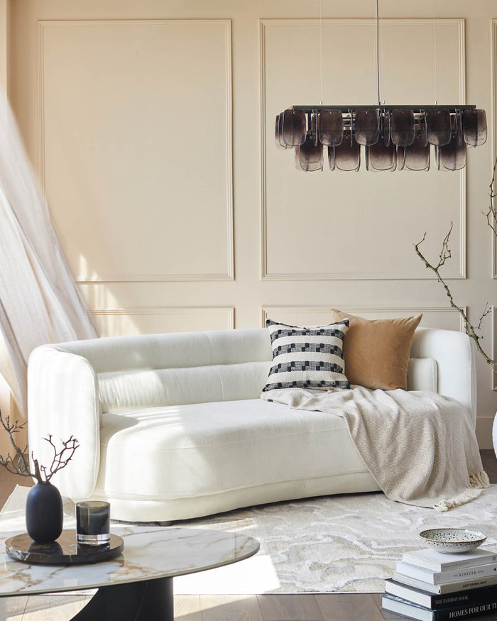 Contemporary living room featuring a stylish white sofa, round marble coffee table, and a modern, decorative chandelier.
