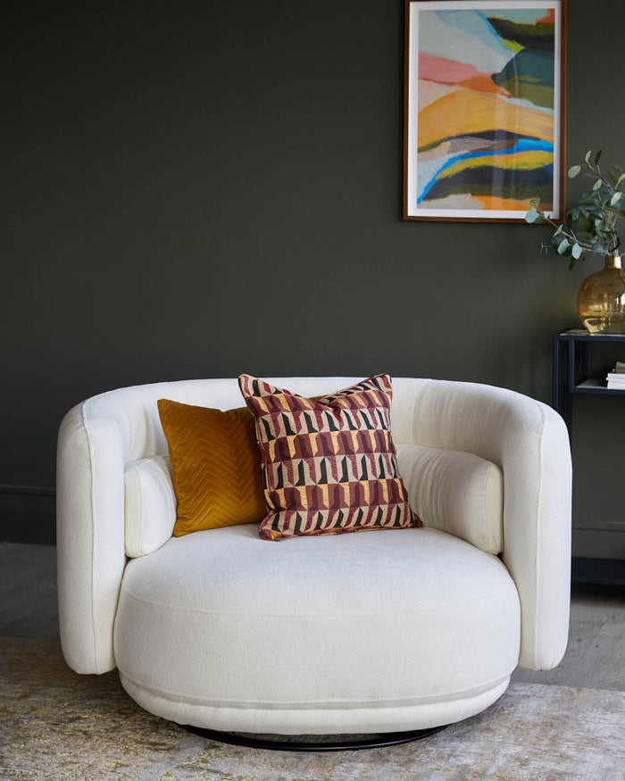 A cosy, round, swivel chair with cushions, set in a stylish room with a framed print and dark green walls.