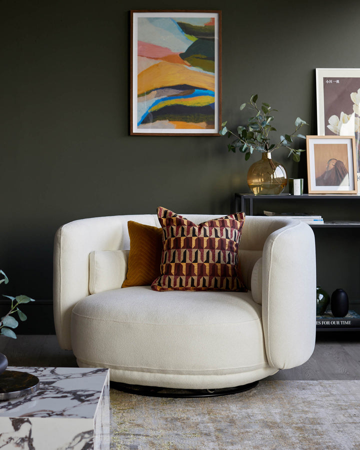 Stylish, comfy swivel chair with patterned cushions, accessorised with side table and framed art creating a cosy space.