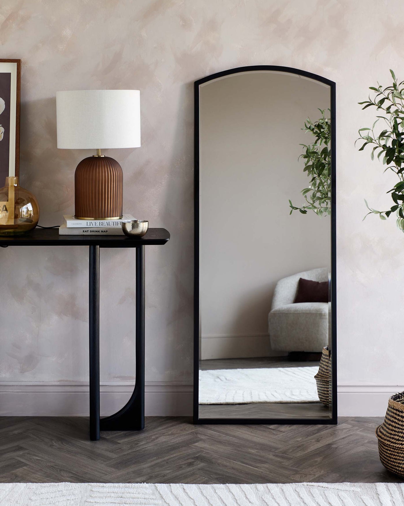 A sleek black console table with a minimalist design and an arch-top full-length floor mirror with a slender black frame.