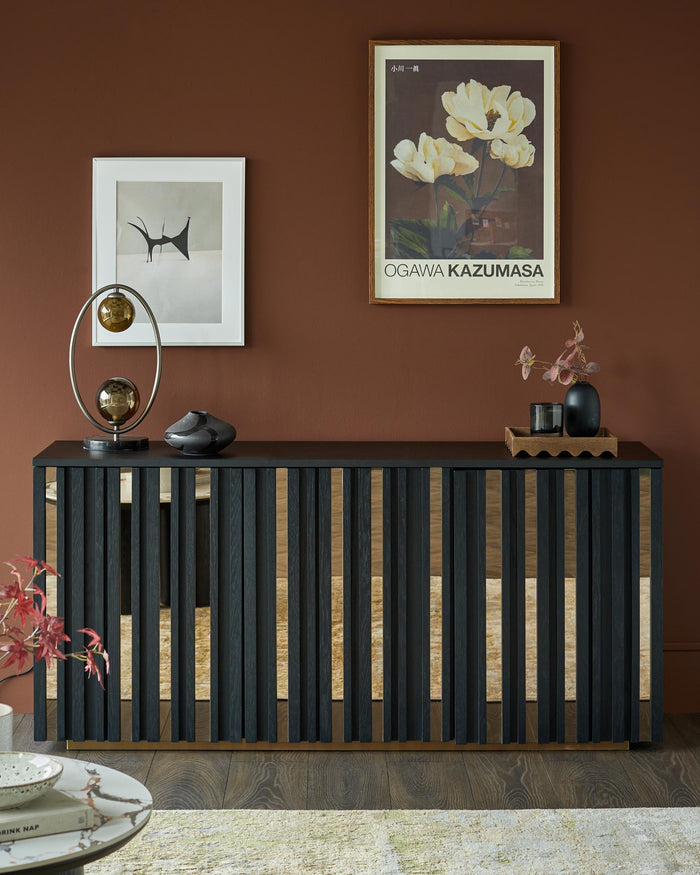 A modern sideboard in dark wood with mirrored detailing, topped with decorative ornaments and artwork on the wall above.