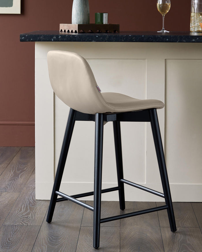 A sleek bar stool with a beige seat and black legs sits stylishly in front of a kitchen island, adding a touch of modern sophistication.
