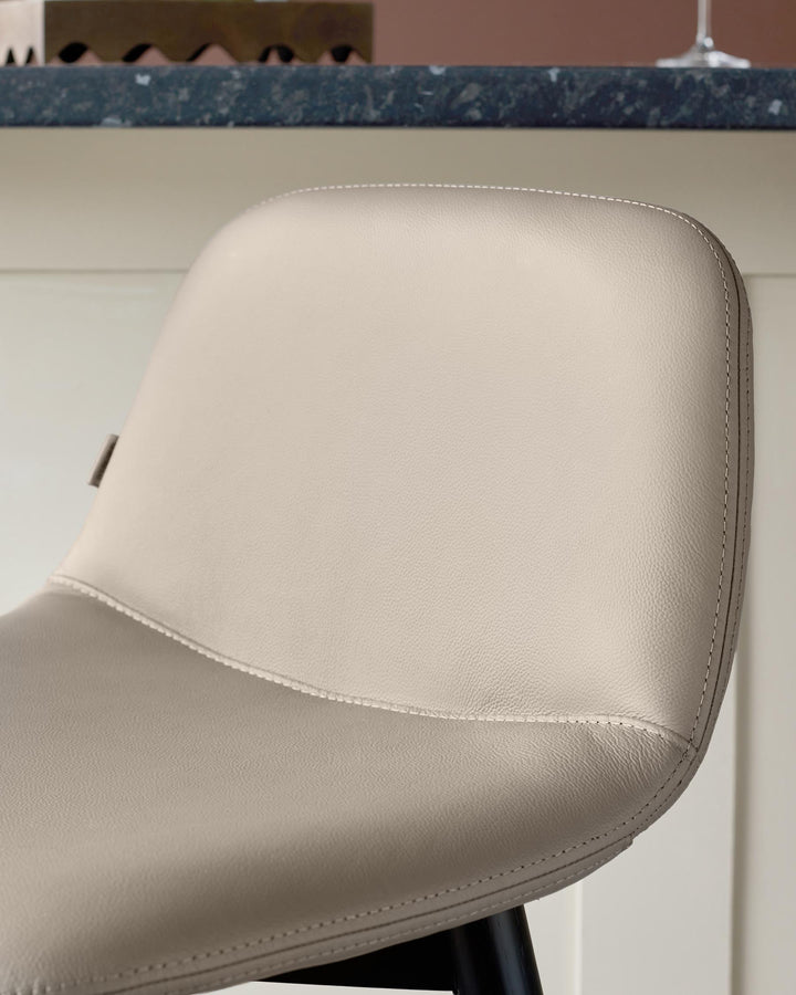 Close up of a cream leather chair, with a black leg, in a modern kitchen. Stylish seating for your home.