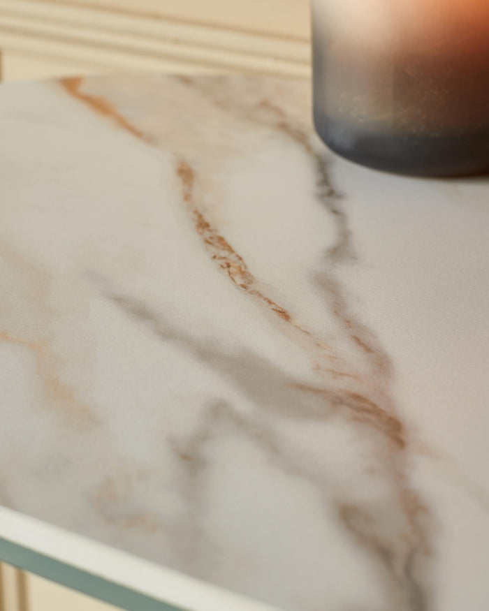 Close-up of a marble-topped table, showcasing its smooth surface and elegant veins. A candle adds a touch of warmth and ambience.