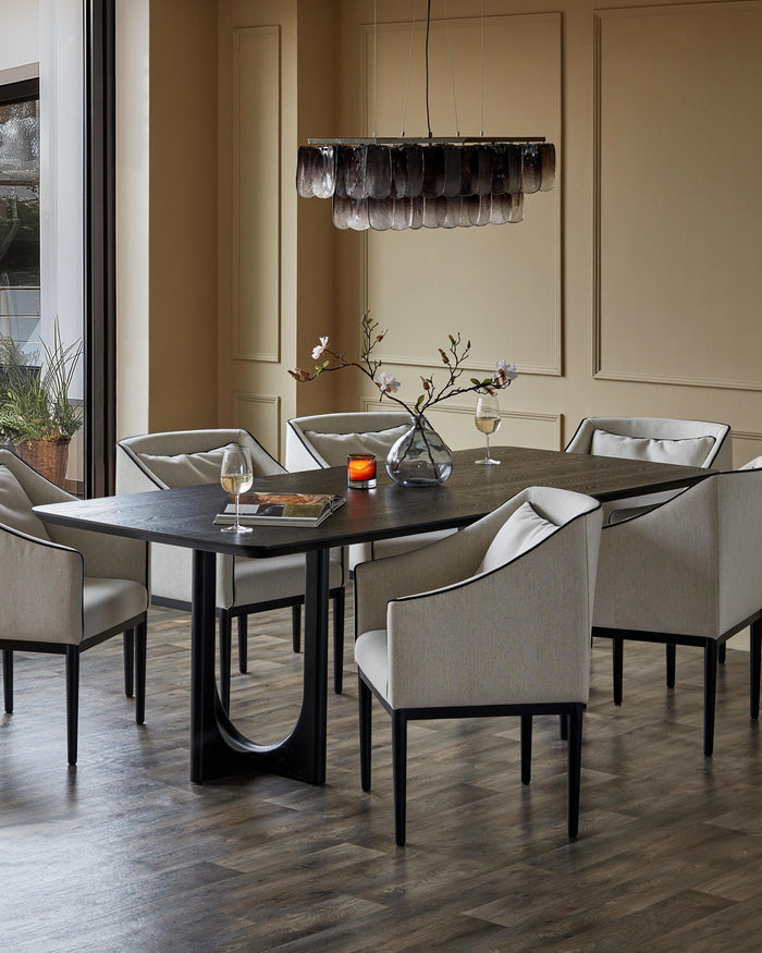 A modern dining set with a dark wooden table, upholstered chairs, and a stylish pendant light, creating an inviting space.