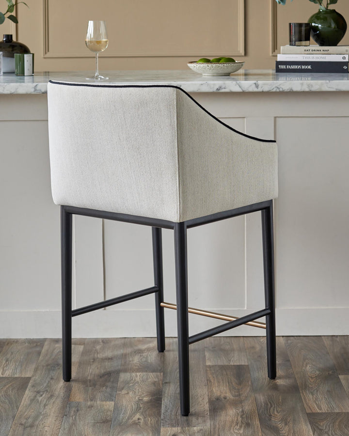 Upholstered bar stool with a black metal frame and light-coloured fabric. Modern design for kitchen or bar area.