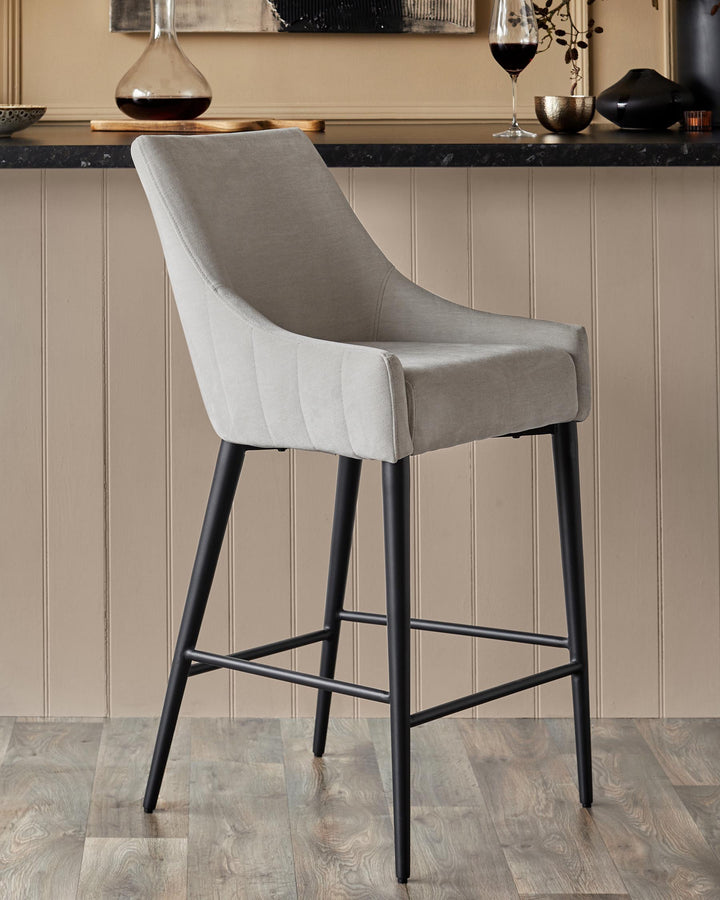 Upholstered bar stool with black legs in front of a bar with decanter, glass of wine, and decorative objects.