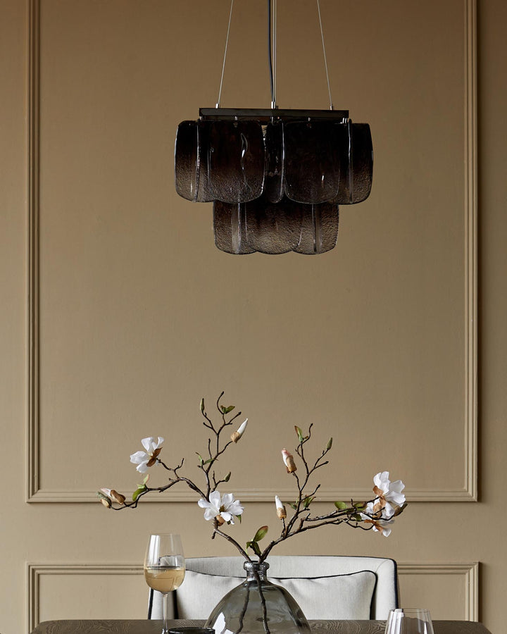 Stylish dining space featuring a glass chandelier above a table with a floral arrangement and elegant tableware.