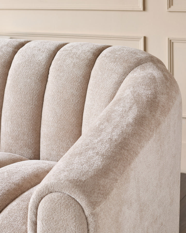 Kendra 3-seater sofa in natural fabric, close-up of curved armrest and channel-quilted backrest detail.