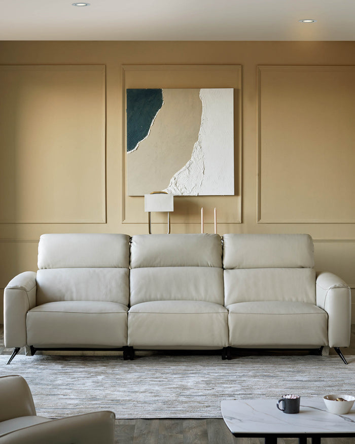 A cream leather recliner sofa with an abstract art piece above. A modern design for comfortable living.