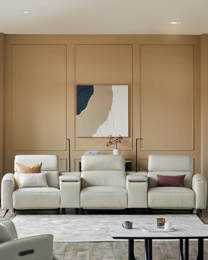 Beige leather three-seater sofa with console, situated atop a neutral rug, with a marble-topped coffee table.