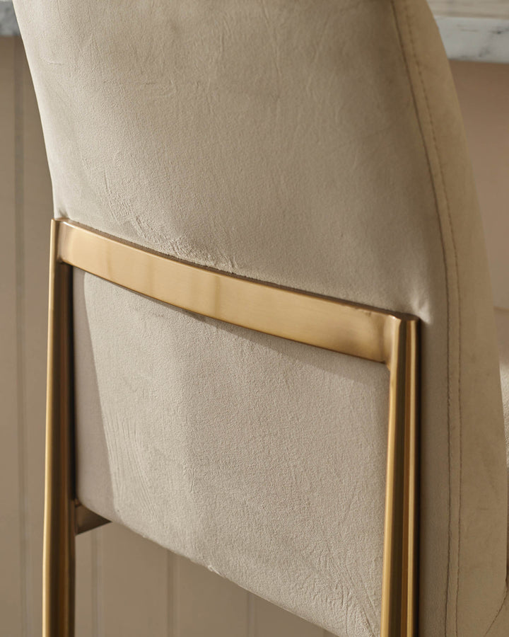 Close-up of a modern chair with a padded back and gold frame. Focus on the material and clean lines.