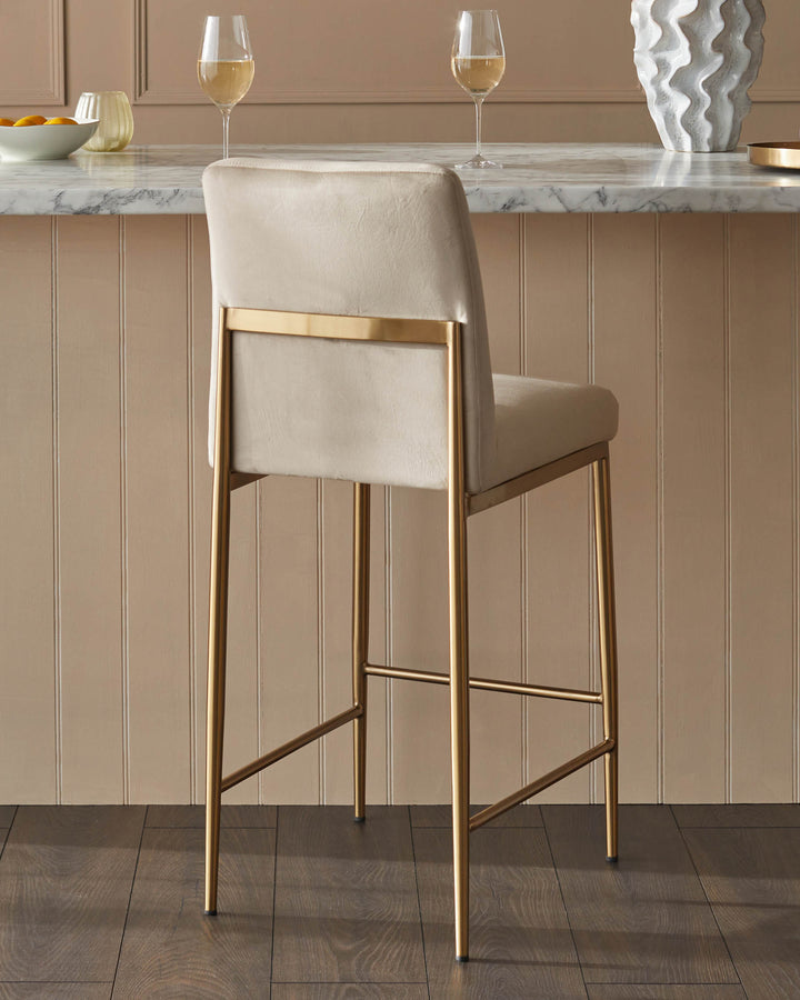 A bar stool with a gold frame and pale cream upholstered seat, perfect for adding a touch of elegance to any kitchen island.