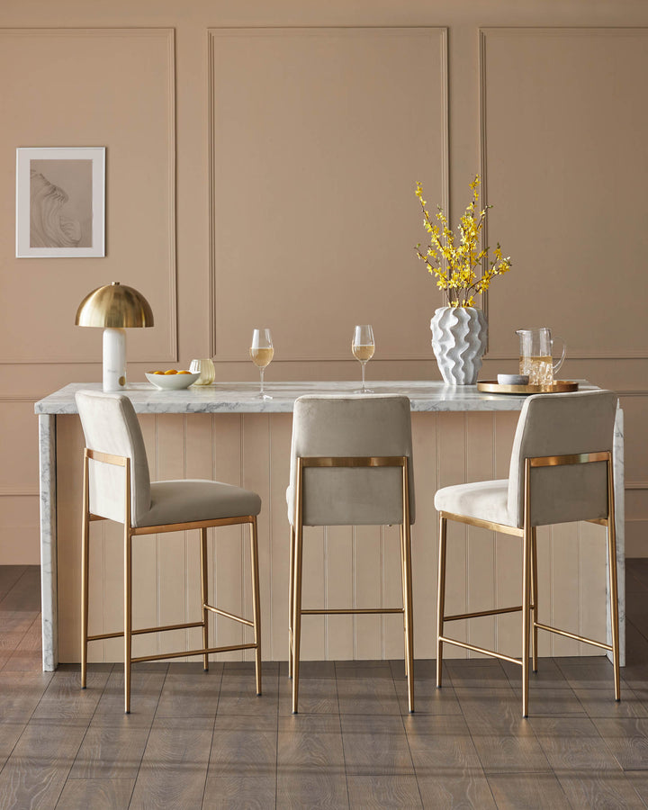 Stylish bar stools with gold frames and neutral upholstery at a marble counter.