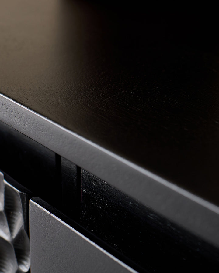 Close-up of black wood sideboard showing polished surface and metal handle detail.