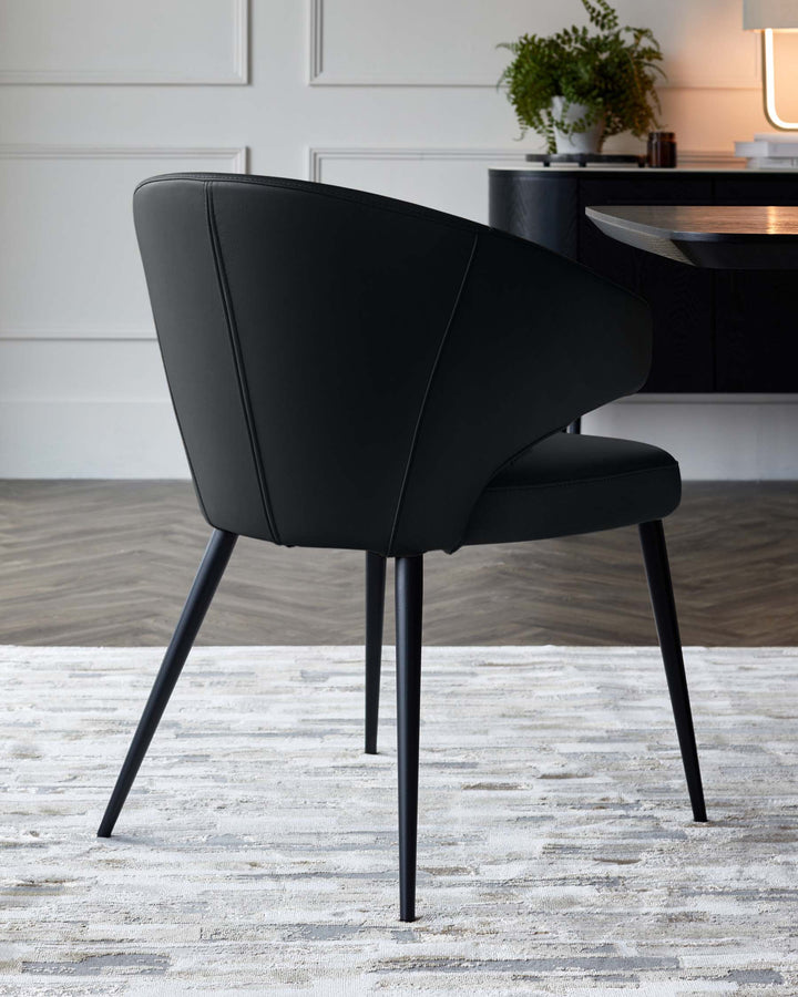 Black leather dining chair with curved back, black metal legs, shown from rear angle in modern dining room setting.
