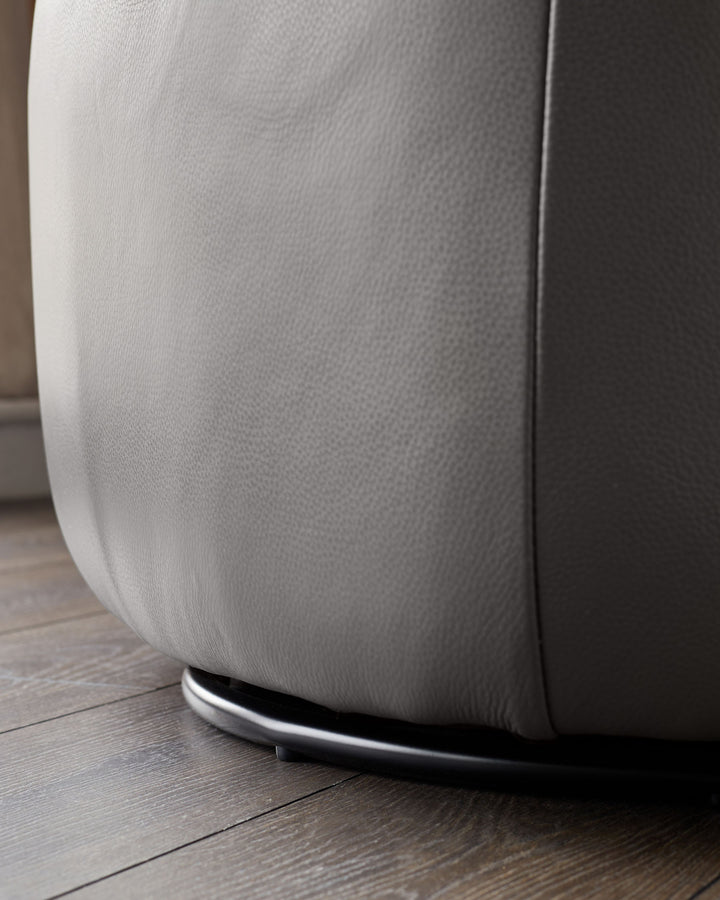 Close-up of a stylish grey leather swivel chair with a sleek, modern base, ideal for a contemporary living space.