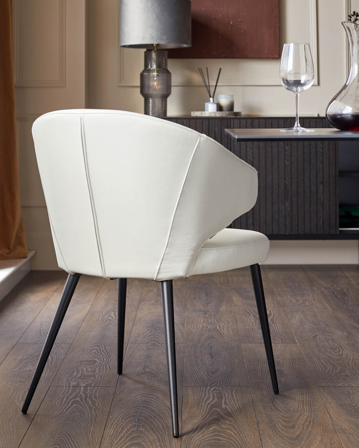 Contemporary dining area with a white upholstered chair and black metal legs, set against a modern dark wood sideboard.