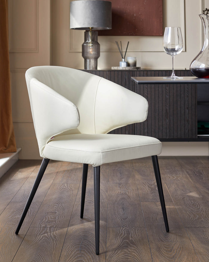 A cream leather dining chair with black metal legs sits in front of a dark wood sideboard.