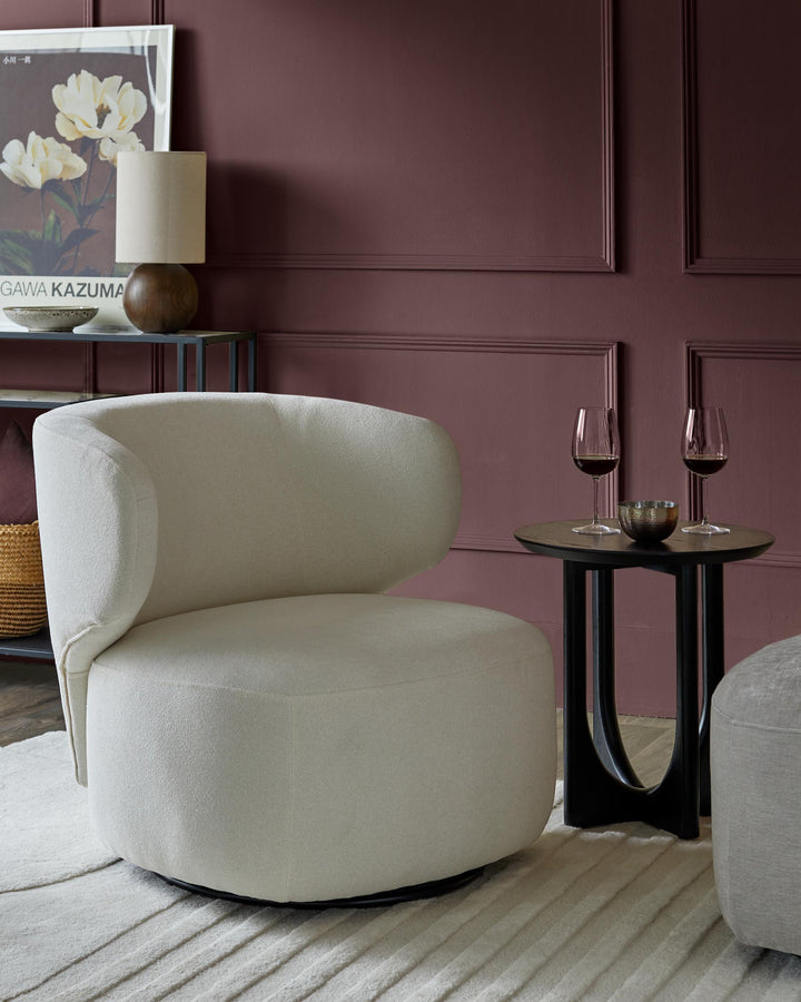 Stylish cream armchair and dark wood side table with wine glasses, adding a touch of luxury to any living space.