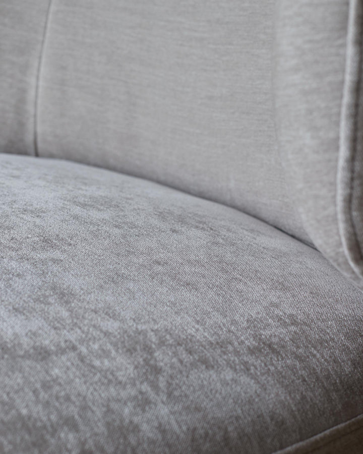 Close up of a grey cushioned chair. The fabric is slightly textured.