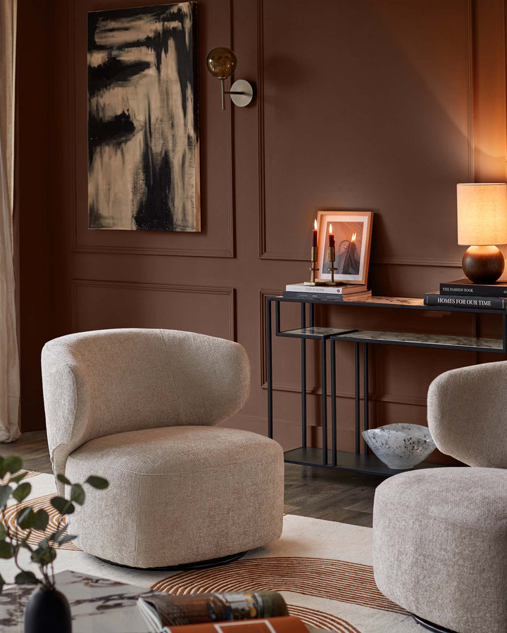 Stylish living room with two contemporary armchairs, dark wood walls and a metal console table.