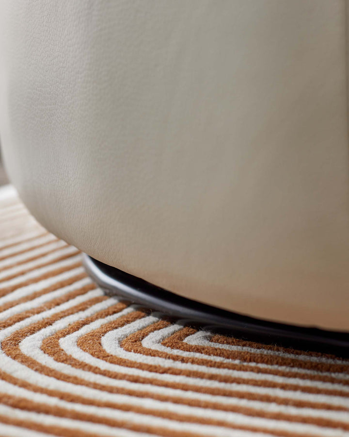 Close-up of a cream-coloured chair base on a patterned rug, showcasing quality craftsmanship and stylish design.