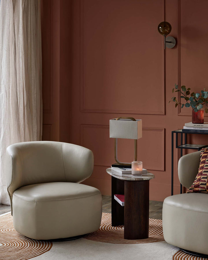 Stylish living room with neutral swivel chairs, a modern side table, and warm-toned decor against a panelled wall.