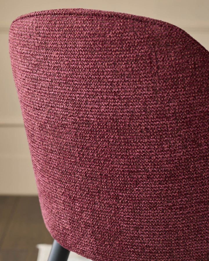 Close-up of a stylish, upholstered chair in a rich, textured fabric. Modern design with a comfortable curve.