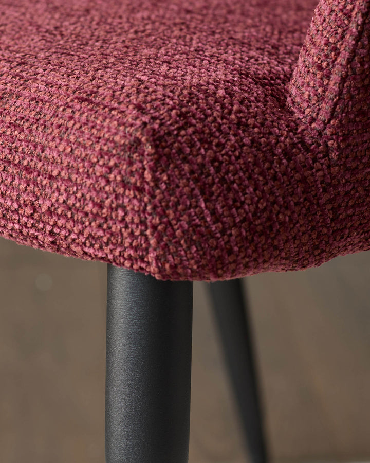 Close-up of a plush, burgundy chair seat and sleek, black legs. Modern comfort meets minimalist design.