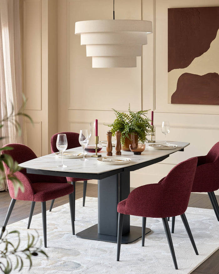 A modern dining set with a marble table, grey stand, red chairs, and a statement pendant light.