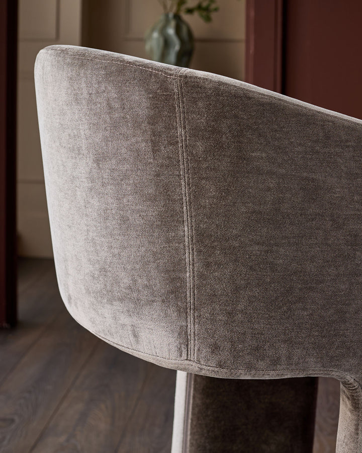 Leighton bar stool in mocha fabric, showing curved backrest detail and brushed bronze cantilever base from side angle.