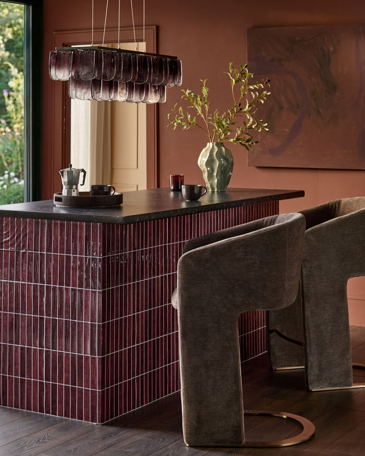 Leighton brushed bronze cantilever bar stool in mocha fabric, shown at dining counter in modern interior setting.