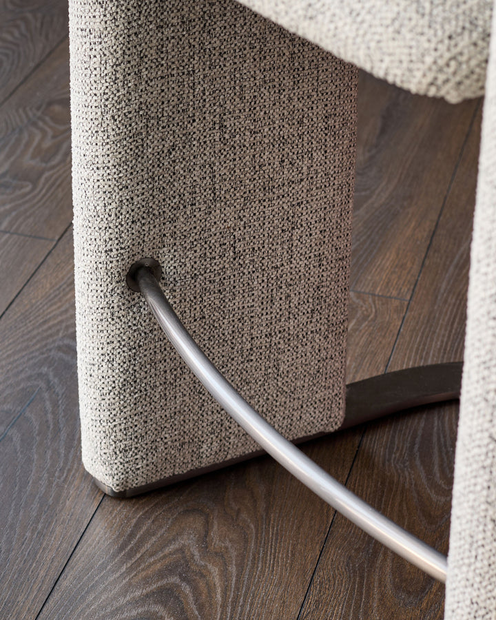 Grey fabric cantilever bar stool with chrome footrest and black steel frame detail.