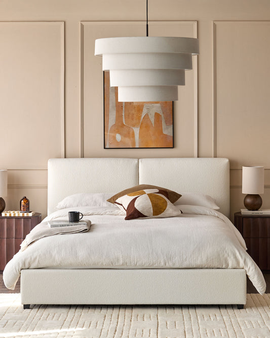 Bedroom featuring a boucle upholstered bed, bedside tables with lamps, and tiered pendant light.