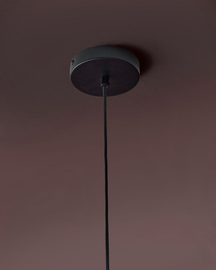 Black pendant light with long cord, ceiling canopy detail visible against mauve wall.