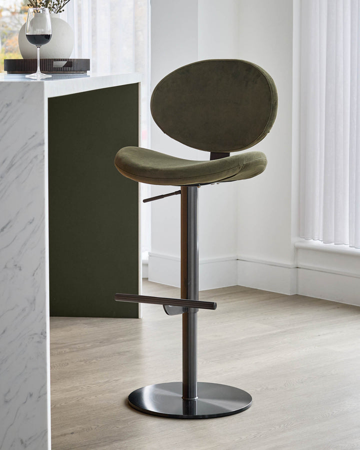 Lilah gas lift bar stool in olive green velvet with oval backrest, walnut wood accents, and black metal base.