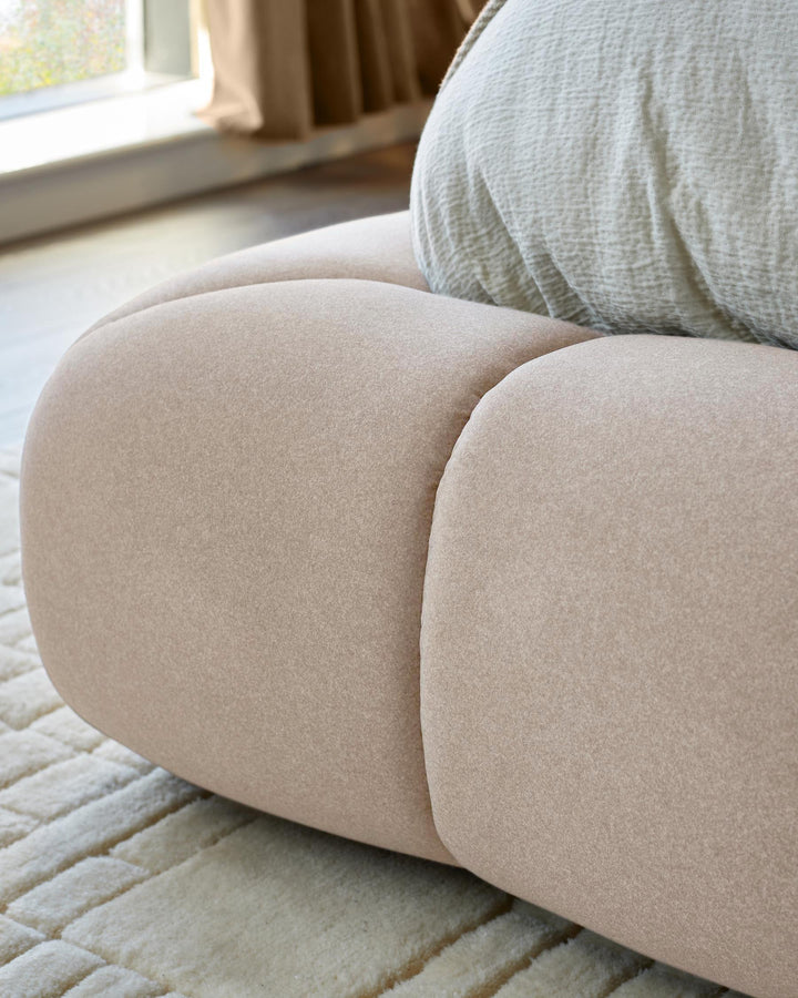 Close-up of a modular sofa in a neutral colour, with a textured rug and a pale green cushion.