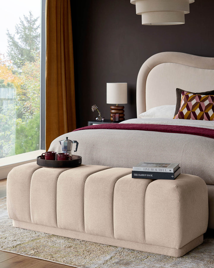 Cream fabric bench with vertical channel quilting, displayed at foot of bed in modern bedroom setting.