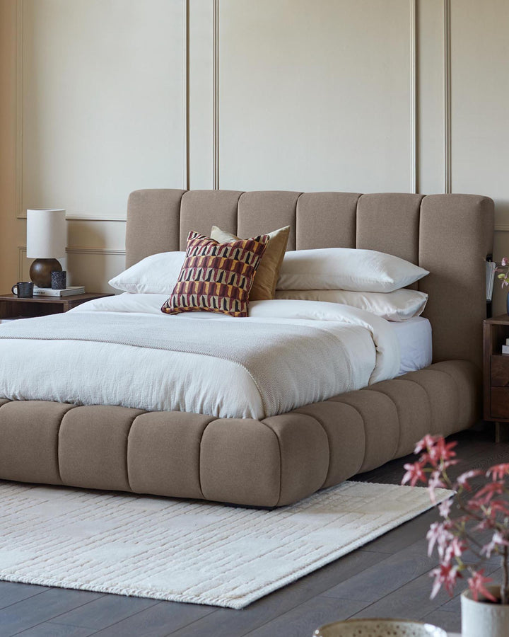 A stylish brown bed takes centre stage, complemented by wooden bedside tables and a neutral rug, creating a cosy bedroom scene.