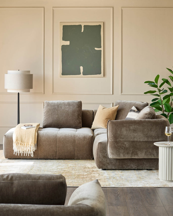 Stylish modular sofa in soft grey velvet, paired with a chic side table, complementing a modern living room aesthetic.