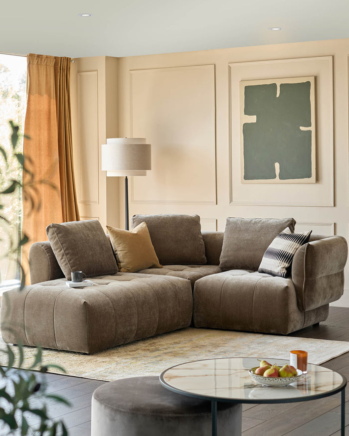 Stylish living room with a modern, modular sofa in a neutral tone, complemented by a round coffee table and soft lighting.
