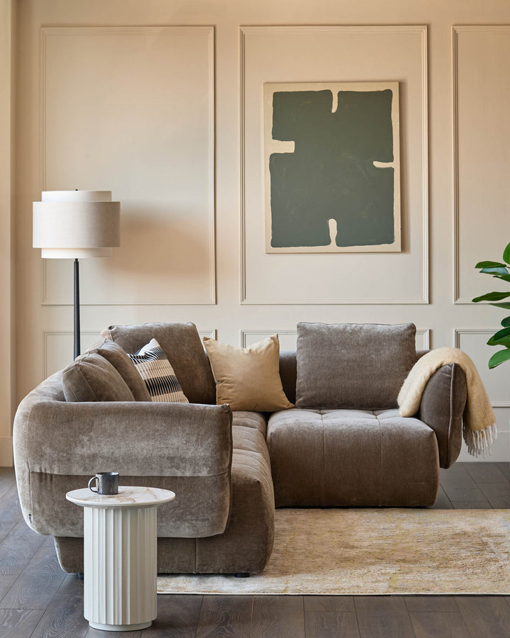 Stylish living room featuring a modular sofa, modern lamp, side table, and abstract artwork.