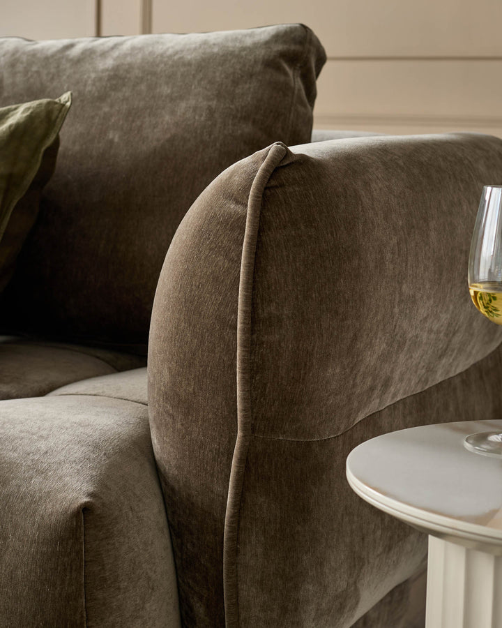 Close-up of a brown sofa with a matching round side table, showcasing textures and contemporary design.