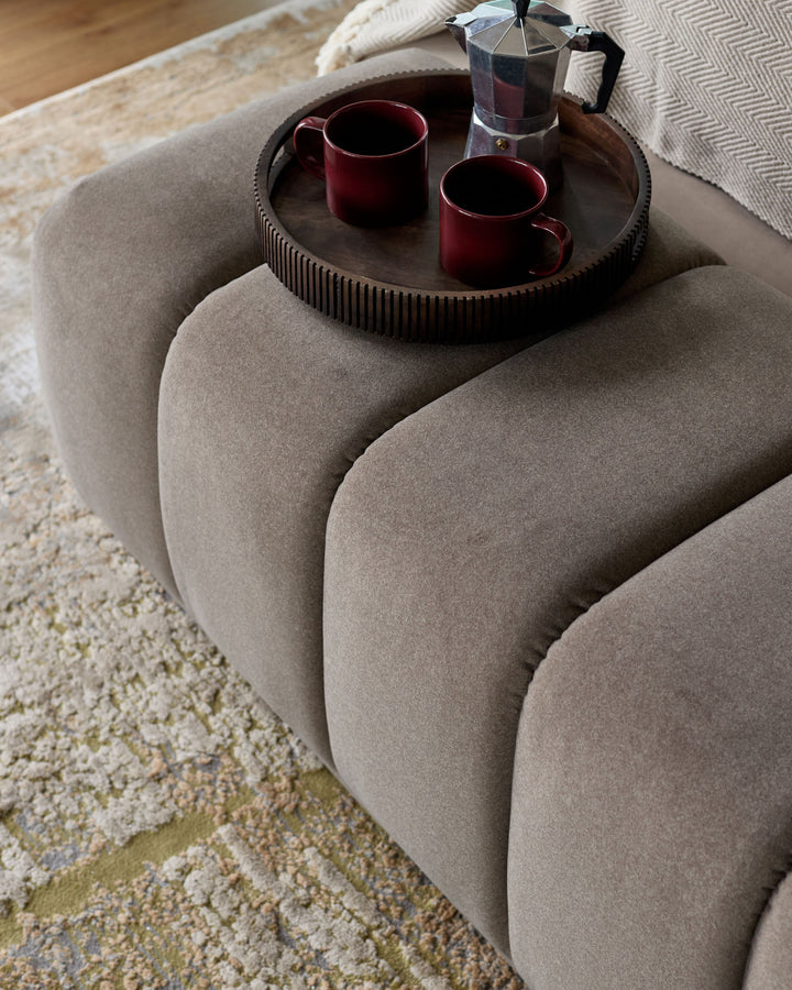 Lillian bench in mocha fabric with curved, rounded edges, styled with a dark tray holding two burgundy mugs and a moka pot.
