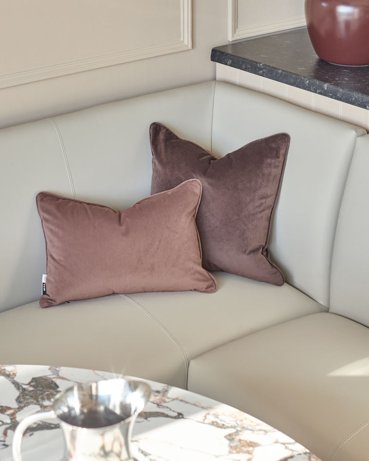 Light grey faux leather corner dining bench with two mauve velvet cushions, chrome legs, styled in modern living room setting.