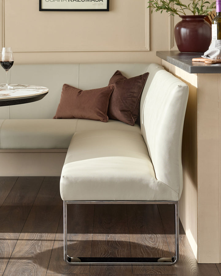 Light grey faux leather corner dining bench with chrome legs, styled with brown cushions in a modern dining setting.