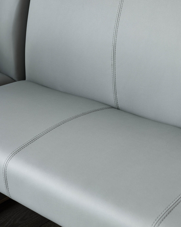 Light grey faux leather corner dining bench with visible stitching detail and curved seat design, close-up view.