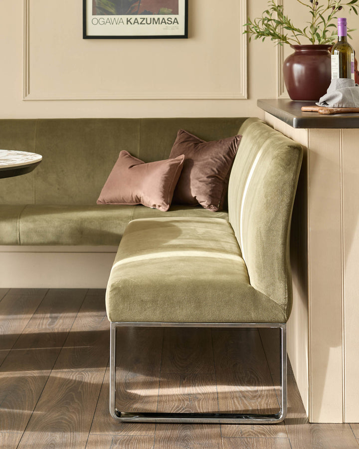 Olive green corner bench with chrome legs, right-hand configuration, styled with cushions in a modern interior setting.