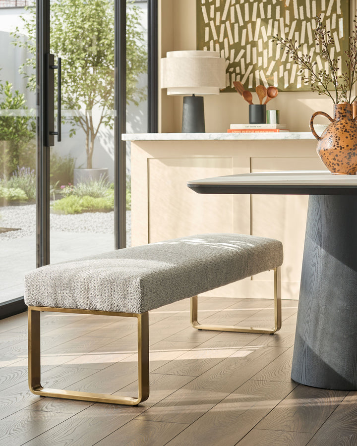 Loop 3-seater fabric bench without backrest in grey with brushed brass frame, styled in modern interior.
